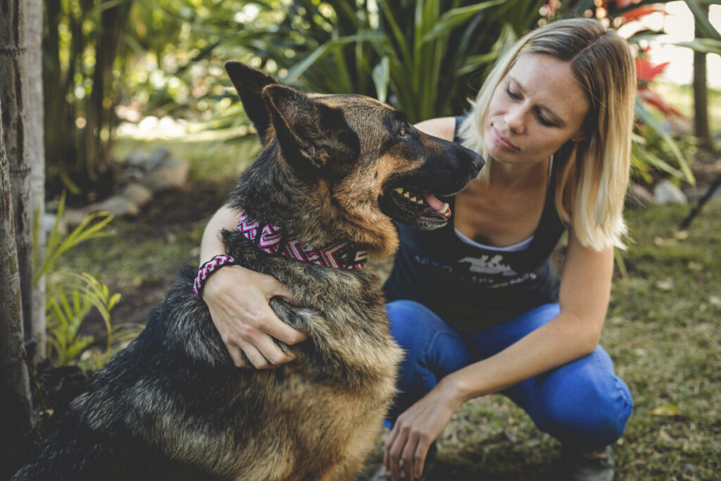 Young woman with arm around her German Shepherd and wristband that matches the collar