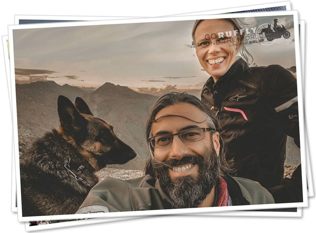 Man and woman motorcycle riders with a German Shepherd at a mountain lookout