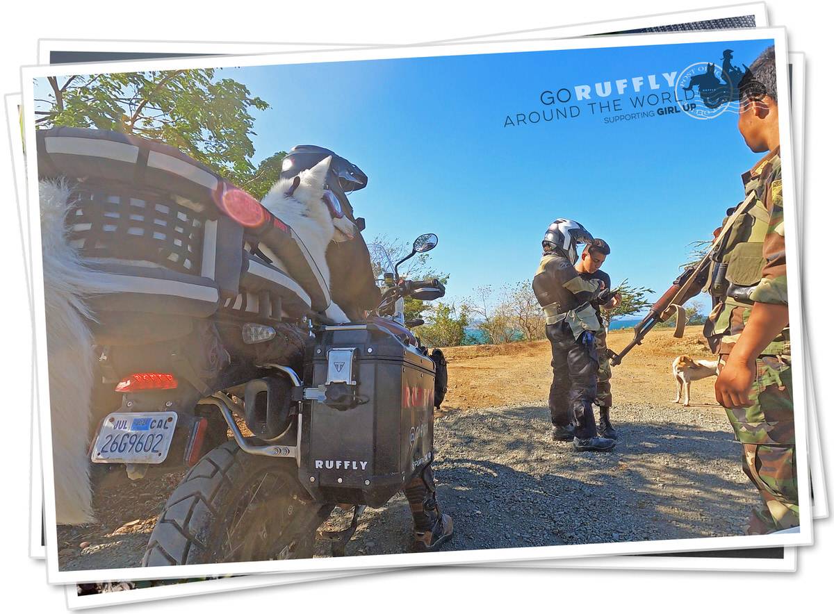 Man talks with soldier while woman and dog sit on motorcycle