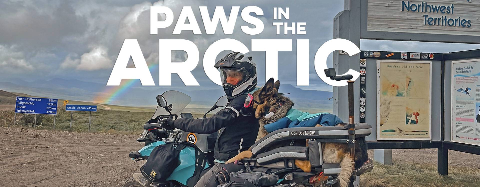 TEMP Motos and Figures Woman on an adventure motorcycle with a German shepherd rides towards the Arctic Ocean with a rainbow