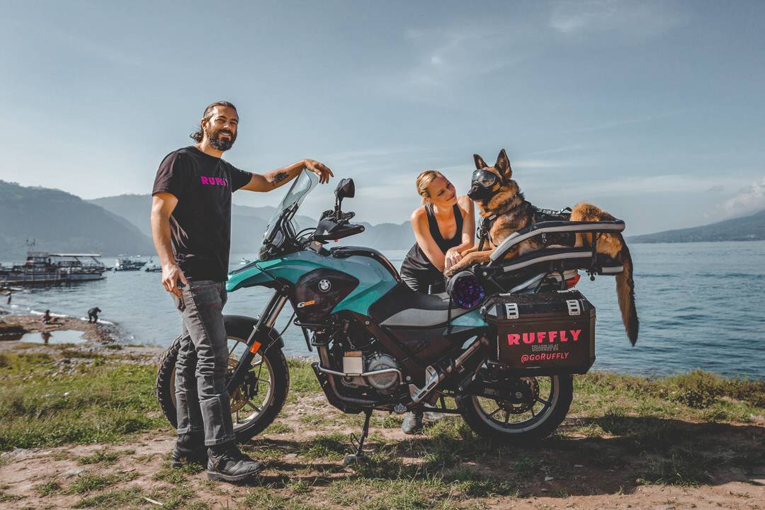 Man, woman, and German shepherd dog with motorcycle at lakeside