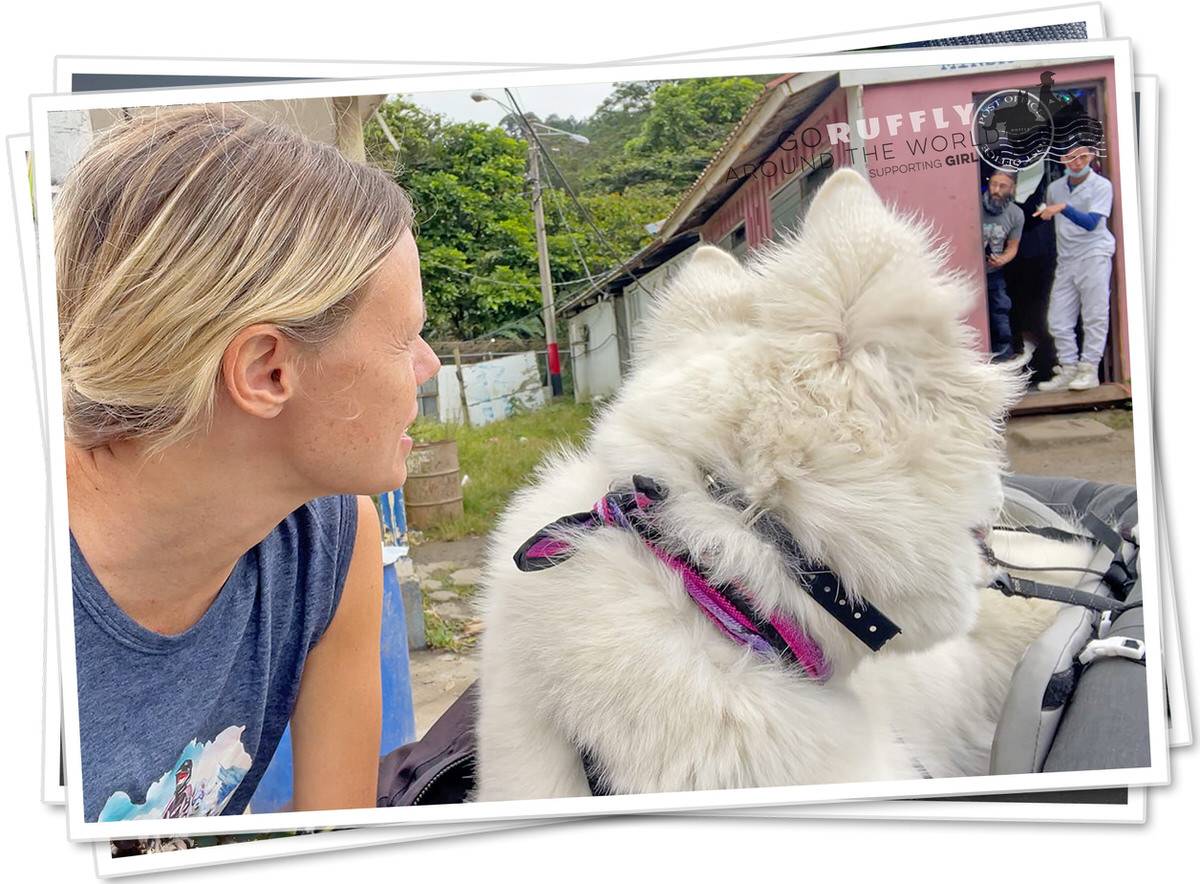 Postcard of woman and white dog at a dirty border outpost