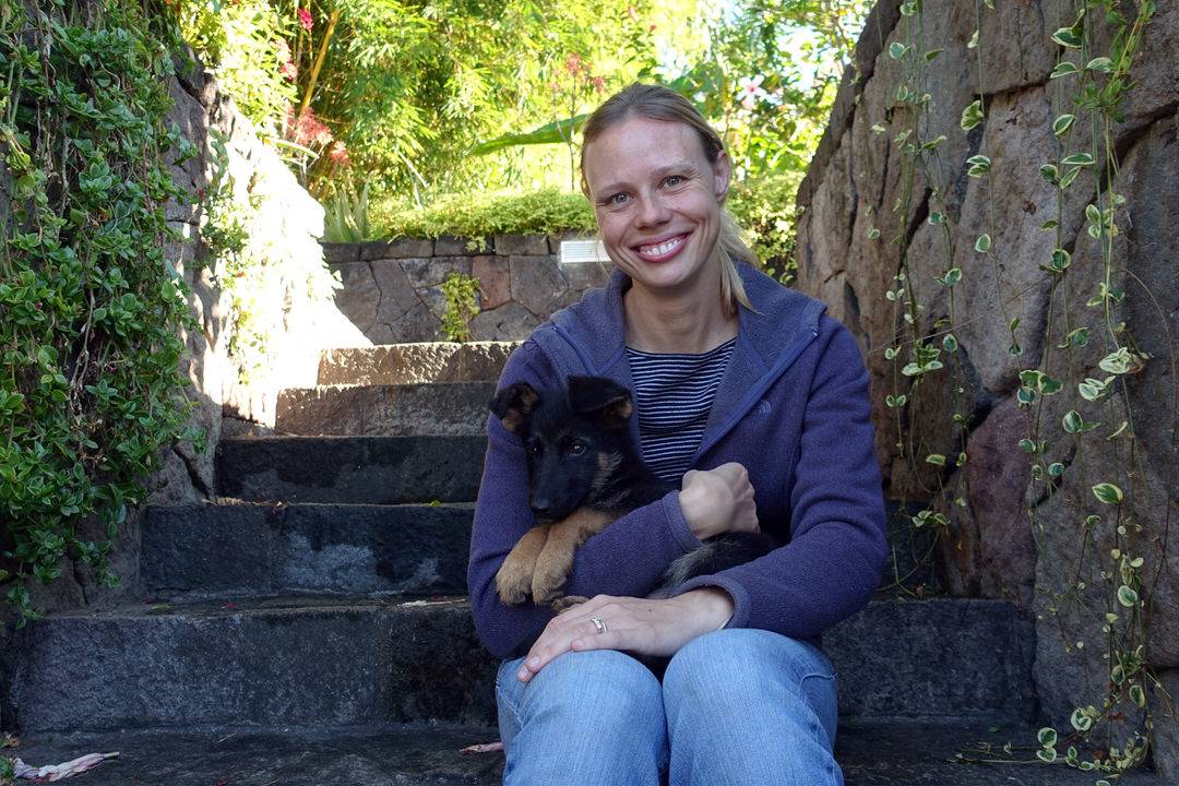 Smiling blond woman hold two-month-old black German shepherd puppy