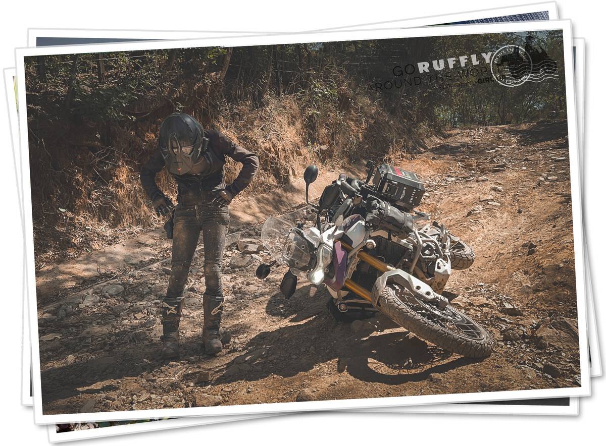 Woman dusts herself off beside a motorcycle after an off-road crash