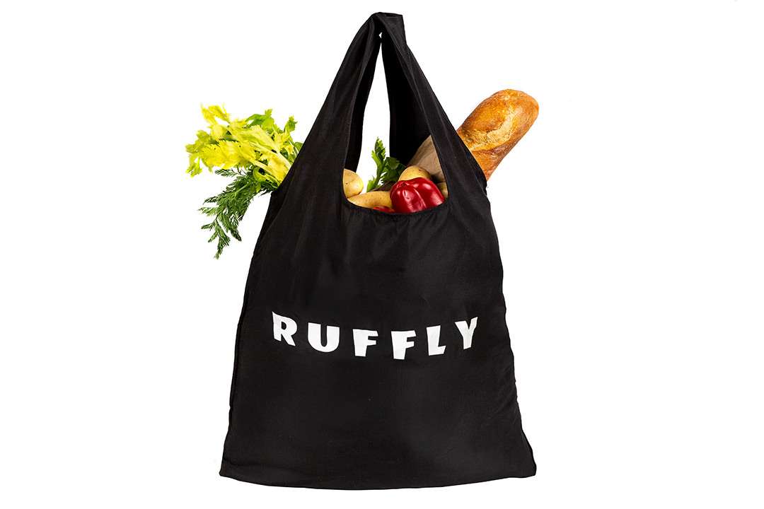 Black, lightweight tote bag filled with variety of fresh groceries and French baguette